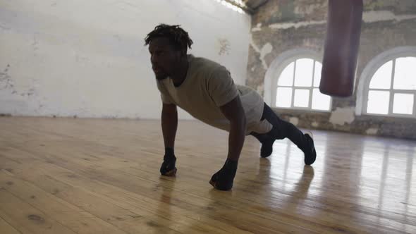 Boxer Doing Pushups on the Floor While Working Out in Old Light Building