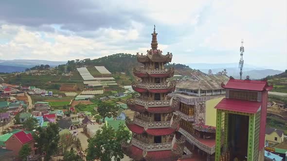 Drone Flies Over Buddhist Multilevel Tower Against Town Hills