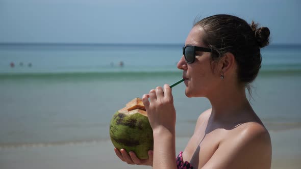 Woman at the Beach Drinks Coconut