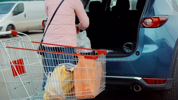 Puts Bags In Trunk Of Car In Mall Parking Lot. Woman Putting Shopping Bags Inside Trunk Supermarket