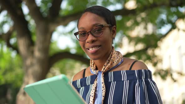 Happy Confident African American Female Student with Tablet in Eyeglasses Smiling Looking at Camera