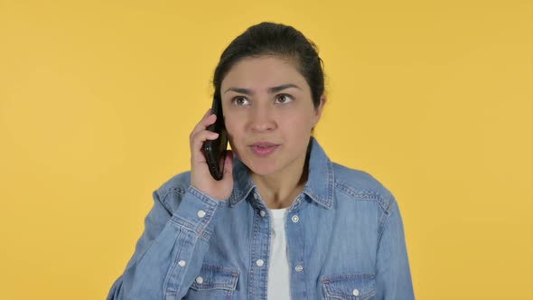 Angry Indian Woman Talking on Smartphone Yellow Background