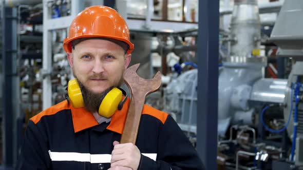 A Closeup of an Oil and Gas Industry Mechanic Stands at the Compressor in a Helmet and Headphones