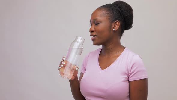 Happy African Woman Drinks Water From Glass Bottle