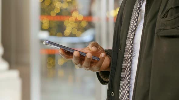 black man's hands typing on cellphone in the crowded street at christmas time