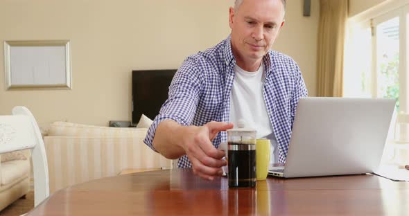 Mature man using laptop while having coffee 4k