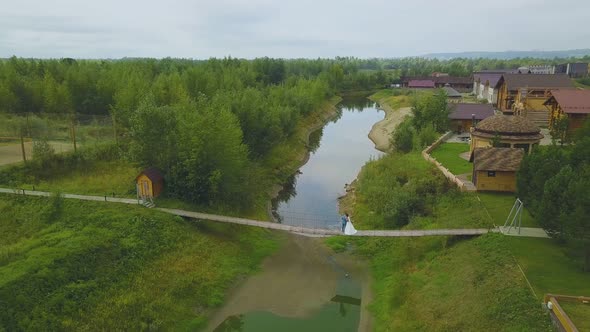 Newlywed Couple on Narrow Bridge Near Cottages Bird Eye View