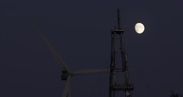 The Windmill Rotates on the Background of the Moon on a Dark Blue Sky