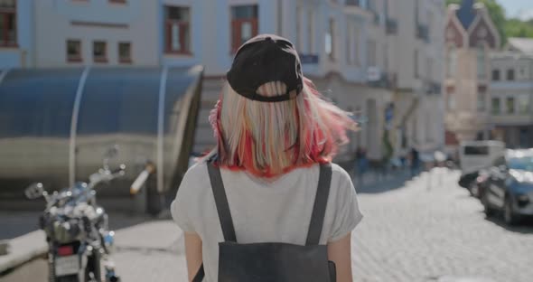 Fashionable Beautiful Teenager Girl with Trendy Colorful Hair Walking Along Street of City, Back