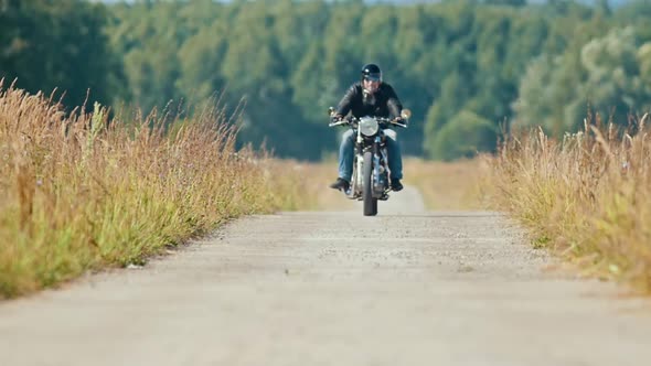 A Man Motorcyclist Riding Motorbike on the Dusty Rye Field Road