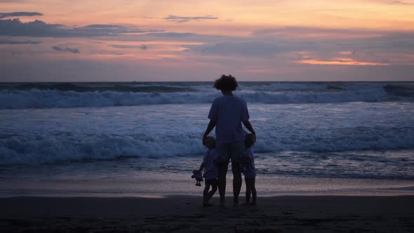 Lovely Family Vacation Silhouette of Single Mother with Two Toddlers Running From Huge Ocean Waves