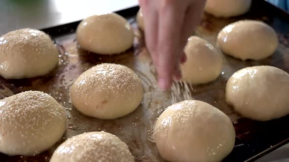 Hand Spreading Sesame Seeds on Dough