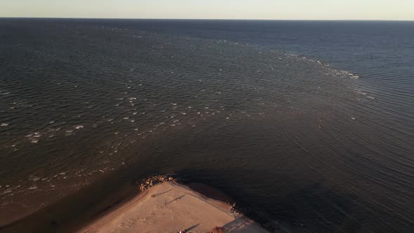 Aerial Fly Up: People Enjoy Scenic Sunset at Cape Kolka Where Riga Gulf Meets Baltic Sea