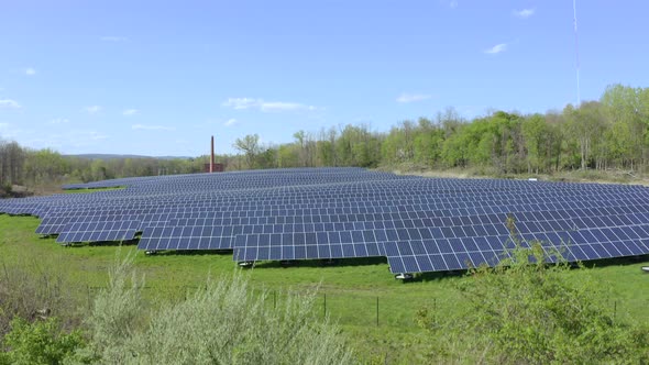 Slow rise reveals solar farm in a field surrounded by trees