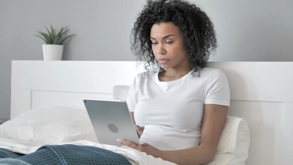 African Woman Browsing Internet on Tablet in Bed