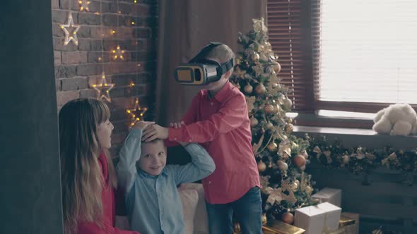 Little Boy in Virtual Reality Glasses Touches Brother Head