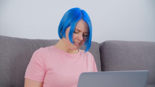 White girl student with blue hair studying online with laptop computer and internet connection