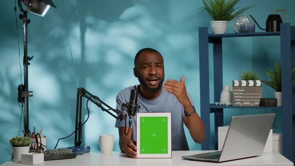 Blogger Vertically Holding Green Screen on Tablet and Filming