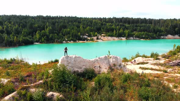 Landscape of a Light Blue Lake Surrounded By Forest - a Successful Man Raises His Hands Up