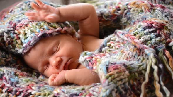 Newborn Baby Sleeps in a Knitted Scarf