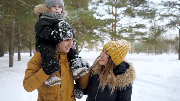 Happy Young Family Are Walking in Winter City Park Together