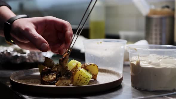 Chef Serves Hot Potatoes with Meat on a Wooden Plate