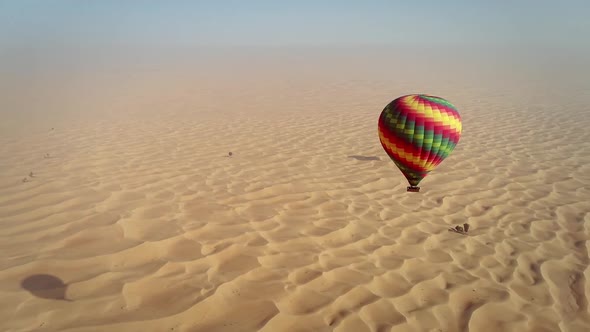 Aerial view of hot-air-balloon flying in the clouds on desert in Dubai, U.A.E.