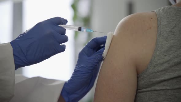 A Nurse Sprays an Antiseptic on a Patient's Shoulder and Then Gives Him a Flu Vaccine