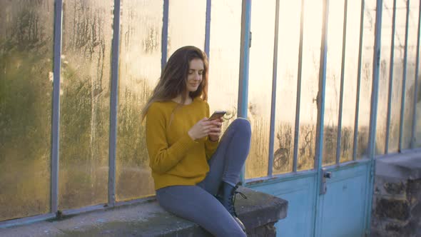 Woman using a smartphone outside of a greenhouse