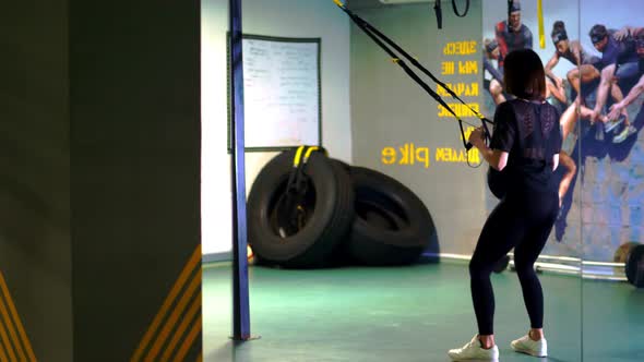 TRX Training. Young Pregnant Athletic Woman, with a Large Belly, in a Black Tight-fitting Tracksuit