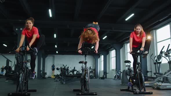 Group of Girls Performs Aerobic Training Workout Cardio Routine on Bike Simulators Cycle Training