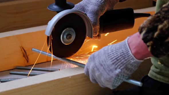 A builder's hands in work gloves cut a metal hairpin with an angle grinder electric tool. Preparatio