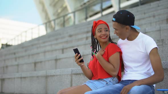 Young Couple Smiling Watching Videos or Reading Posts in Social Network on Phone