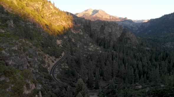 Aerial view of a car driving down Sonora Pass in the Sierra Nevada mountain range at sunset.