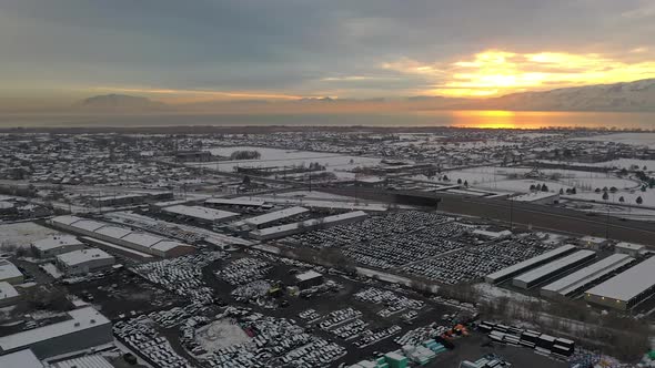 Panning aerial view over wrecking yard in winter at sunset