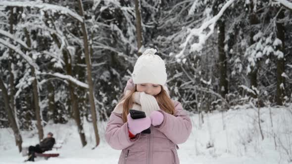 Little Girl Portrait in Winter Writes a Message on a Mobile Phone
