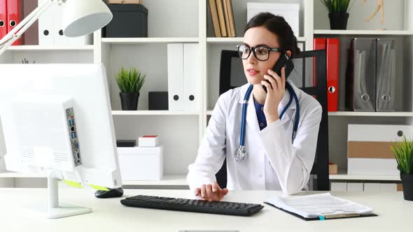Doctor Is Talking on Phone and Looking at Monitor