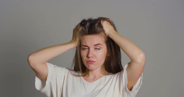 Portrait of a Young Woman Who Cannot Make a Decision She Keeps Her Hands in Her Hair and is on the