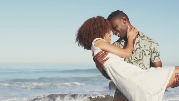 African American man holding his wife seaside