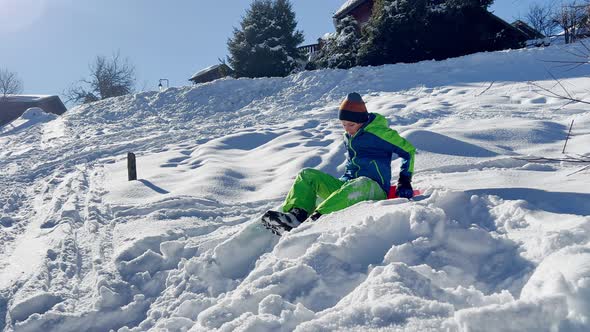 Boy Sled Downhill on Snow Over the Mountain Peaks