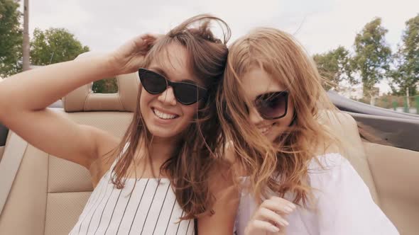 Portrait of two young beautiful and smiling hipster girls in convertible car