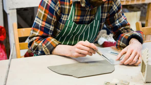 Male potter molding a piece of flat clay