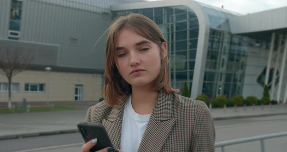 A Young Girl Is Texting Message and Smiling. Travel By Plane. Sunny Weather