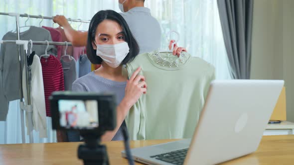 Asian young business couple selling product online live streaming during covid pandemic in house.