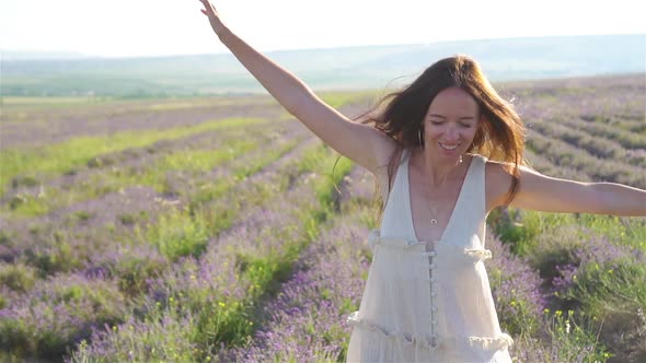 Woman in Lavender Flowers Field at Sunset in White Dress and Hat