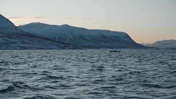 Small Fishing Boat with Small Wooden Houses on the Banks Near Fjords of Tromso in Winter. Dark Blue