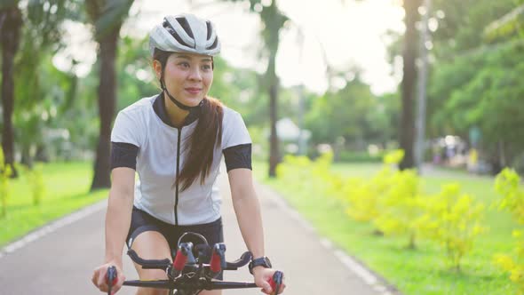 Asian young beautiful woman in sportswear riding bicycle for health in the evening in public park.