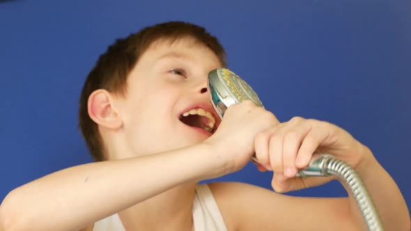 attractive caucasian boy 7 years old sings in the shower imitating a microphone