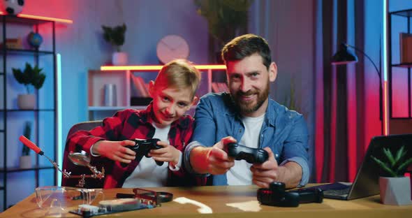 Bearded Dad and Teen Son Enjoying Videogames and Celebrating Victory