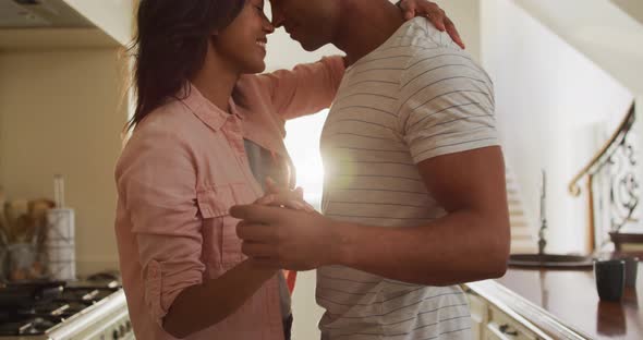 Happy biracial couple dancing together in kitchen